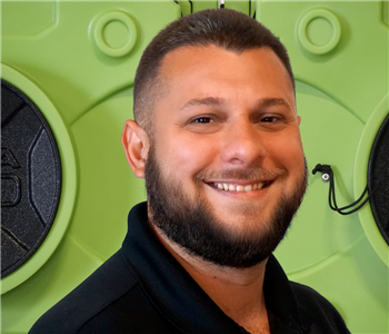 Operations Manager, smiling man with beard, in SERVPRO hat, standing in front of green equipment