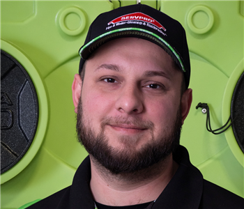 Operations Manager, smiling man with beard, in SERVPRO hat, standing in front of green equipment