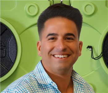 Franchise owner - Smiling man in front of green equipment