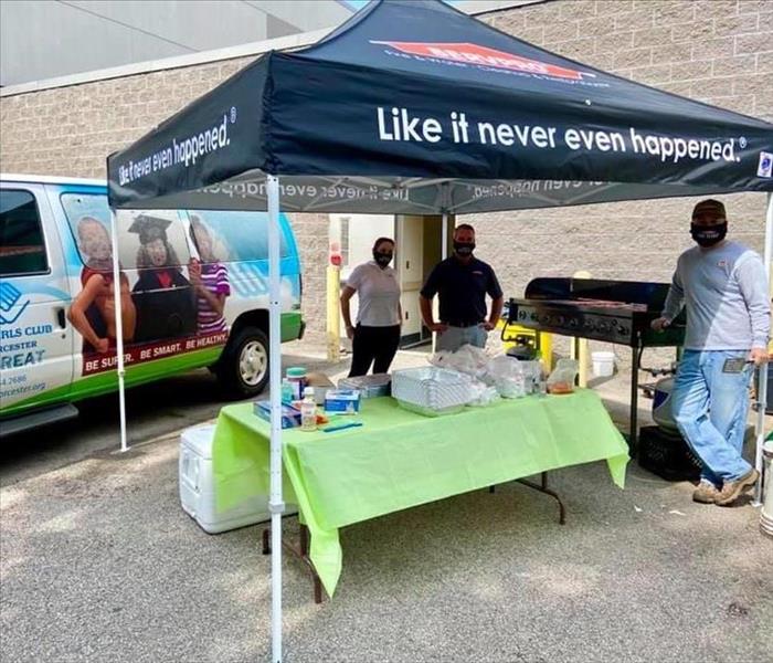 SERVPRO Team under a SERVPRO Tent, next to Boys and Girls Club van, setting up for a BBQ