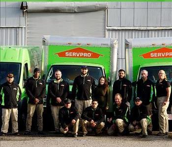 SERVPRO production crew. Smiling employees standing in front of SERVPRO trucks.